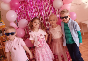 Dzieci pozują do pamiątkowego zdjęcia podczas przedszkolnego Dnia Kobiet w stylu Barbie