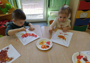 Dzieci kolorują farbami rysunek - kura