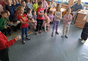 Dzieci przeprowadzają ćwiczenie tworząc sieć z wełny