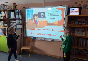 Dzieci wskazują zasady bezpieczeństwa w sieci na tablicy multimedialnej