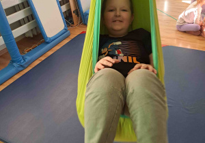 Chłopiec huśta się na huśtawce terapeutycznej