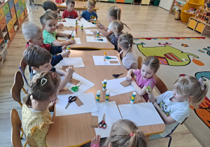 Dzieci przy stoliku wykonują pracę plastyczną