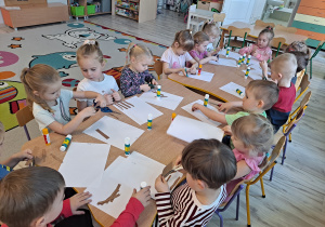 Dzieci przy stoliku wykonują pracę plastyczną