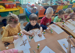 Dzieci przy stoliku wykonują pracę plastyczną