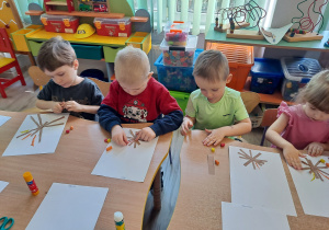 Dzieci przy stoliku wykonują pracę plastyczną