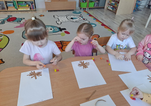 Dzieci przy stoliku wykonują pracę plastyczną