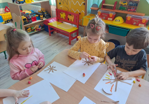 Dzieci przy stoliku wykonują pracę plastyczną