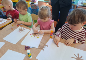 Dzieci przy stoliku wykonują pracę plastyczną