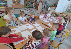 Dzieci przy stoliku wykonują pracę plastyczną
