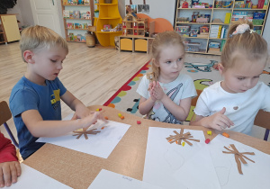 Dzieci przy stoliku wykonują pracę plastyczną