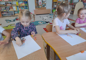 Dzieci przy stoliku wykonują pracę plastyczną