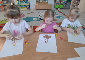 Dzieci przy stoliku wykonują pracę plastyczną