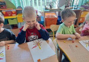 Dzieci przy stoliku wykonują pracę plastyczną