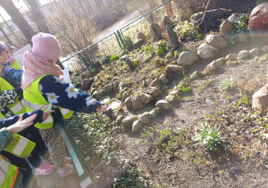 Dziewczynka wskazuje ręką na przebiśniegi