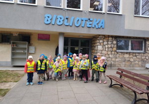 Dzieci podczas wyjścia do biblioteki pozują do wspólnego zdjęcia przed budynkiem