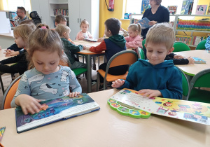 Dzieci podczas wizyty w bibliotece oglądają książki
