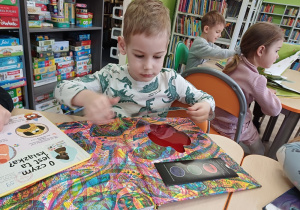 Chłopiec podczas wizyty w bibliotece ogląda książki