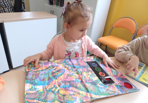 Dziewczynka podczas wizyty w bibliotece ogląda książki