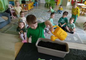 Chłopiec podlewa nasiona