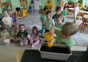 Chłopiec podlewa nasiona