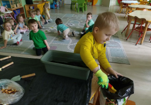 Chłopiec wsypuje ziemię do doniczki