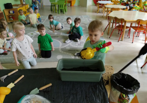 Chłopiec wsypuje ziemię do doniczki