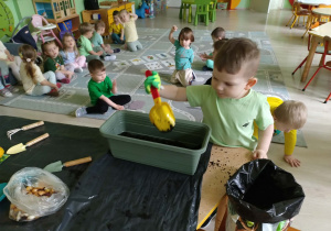 Chłopiec wsypuje ziemię do doniczki