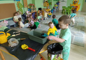 Chłopiec wsypuje ziemię do doniczki