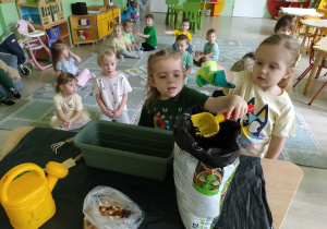 Dziewczynki wsypują ziemię do doniczki