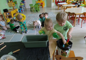 Dzieci wsypują ziemię do doniczki