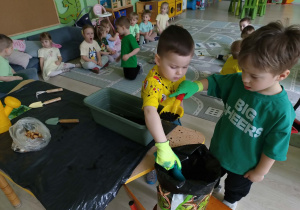 Chłopcy wsypują ziemię do doniczki