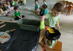Chłopiec wsypuje ziemię do doniczki