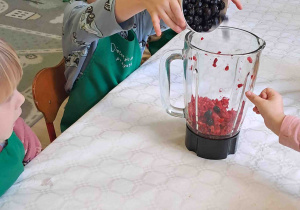 Dzieci wsypują owoce do blendera