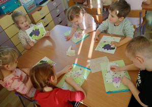 Dzieci kolorują kwiatki dla dziewczynek z okazji Dnia Kobiet.