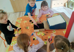 Dzieci wsypują ziemię do ekologicznych doniczek.