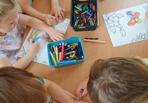 Dzieci kolorują wiosenny obrazek.