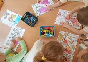 Dzieci kolorują wiosenny obrazek.