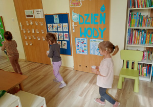 Dzieci przenoszą kubeczek z wodą do stoliczka, by móc napić się jej.