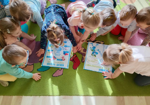 Dzieci oglądają tablice demonstracyjne z ciekawostkami o wodzie i zdrowym stylu życia.