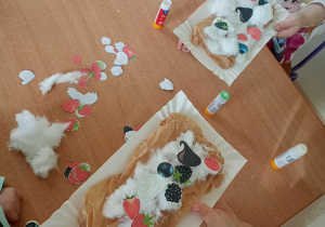 Dzieci prezentują, jakie owoce z papieru nakleiły na bitą śmietanę z waty.