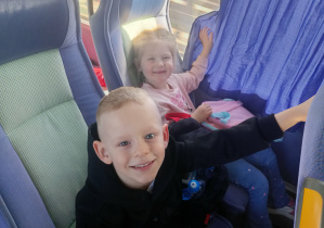 Dzieci wesoło pozują do zdjęcia w autokarze.