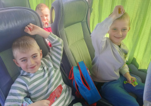 Dzieci wesoło pozują do zdjęcia w autokarze.