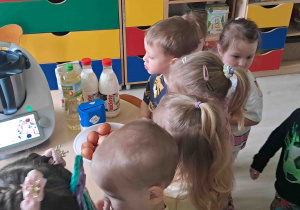 Dzieci przyglądają się robotowi w którym powstanie ciasto na gofry