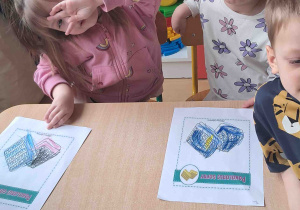Dzieci przy stoliku wykonują karty pracy w tematyce Dnia Gofra