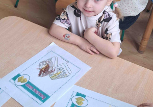 Dzieci przy stoliku wykonują karty pracy w tematyce Dnia Gofra