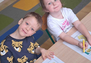 Dzieci przy stoliku wykonują karty pracy w tematyce Dnia Gofra