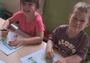 Dzieci przy stoliku wykonują karty pracy w tematyce Dnia Gofra