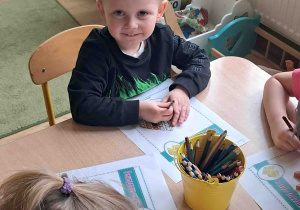 Dzieci przy stoliku wykonują karty pracy w tematyce Dnia Gofra