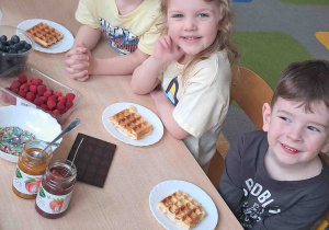Dzieci przy stoliku przyrządzały gofry według własnego uznania