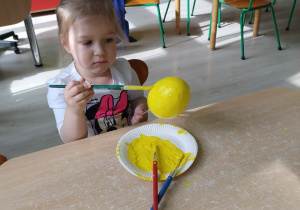 Dziewczynka koloruje styropianowe jajko